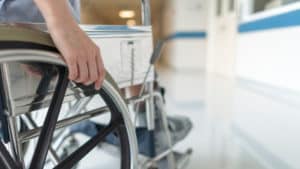 Person in wheelchair facing maximum medical improvement for paralysis injuries after accident.