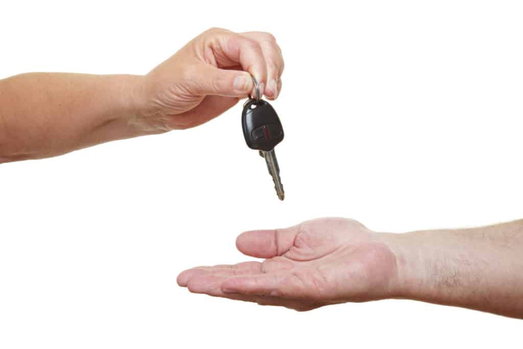 person handing over a car key to a non-owner driver